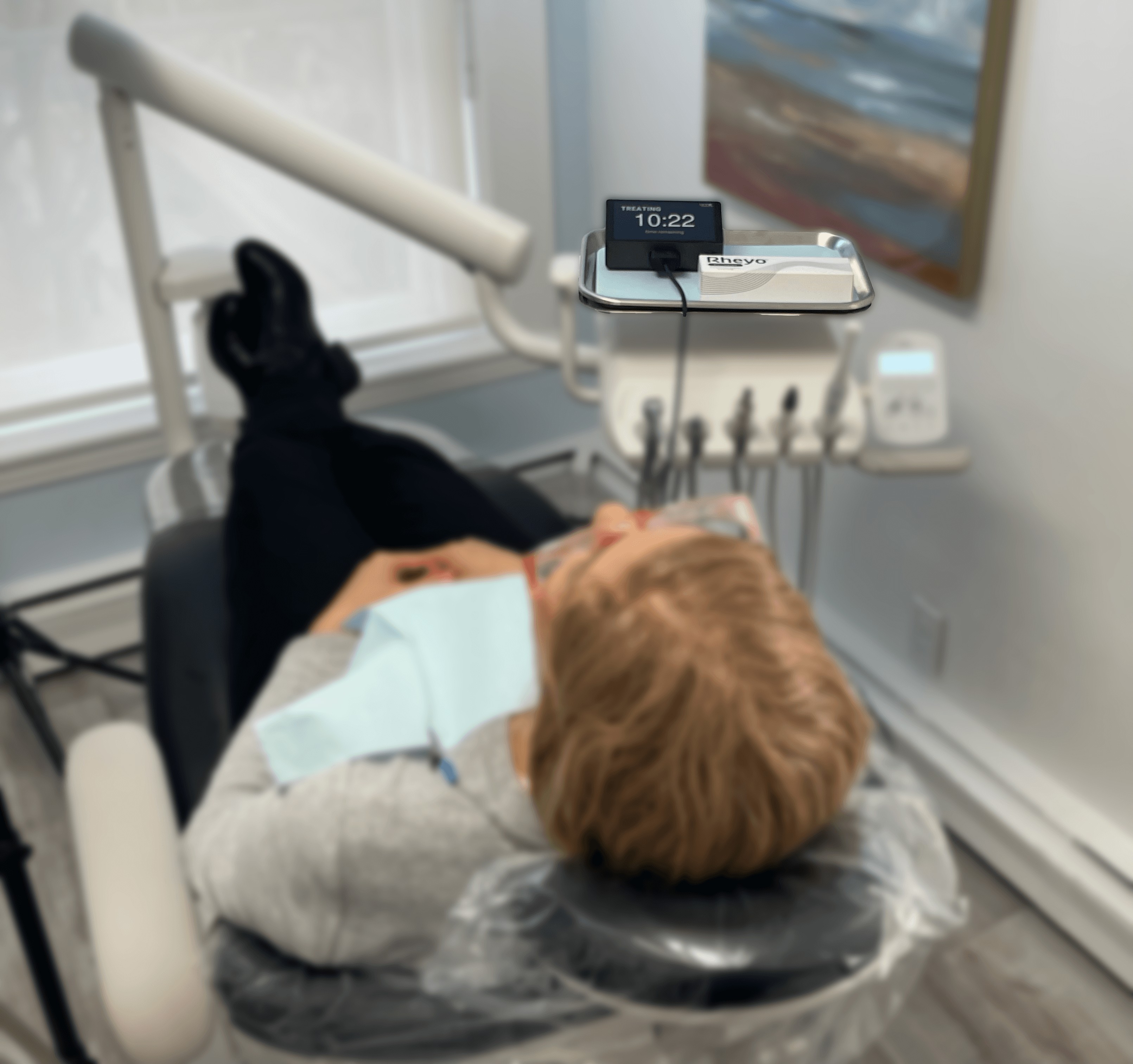 Patient receiving Rheyo whitening treatment chairside — device showing treatment timer